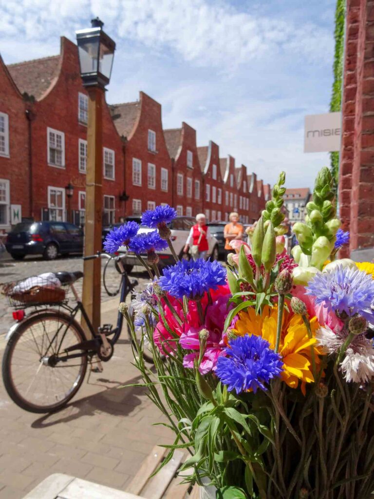 Rote Backsteinhäuser, Fahrrad und bunte Blumen in einem Café im Holländischen Viertel von Potsdam. Foto: Lisa Freudlsperger