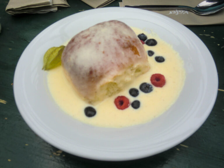 Dampfnudel mit Vanillesoße in einem Teller mit Beeren dekoriert.