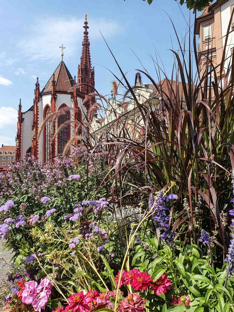 Kirche mit rotem Turm, im Vordergrund bunte Blumen Foto: Lisa Freudlsperger