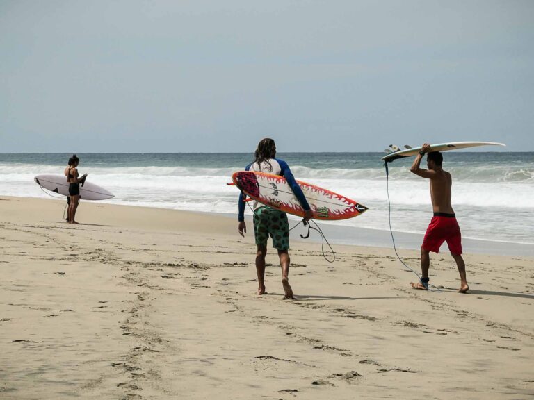 Drei Surfer auf dem Weg ins Meer. Foto: Lisa Freudlsperger