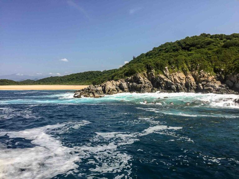 Blick auf Felsen und Sandstrand vom Boot aus. Foto: Lisa Freudlsperger