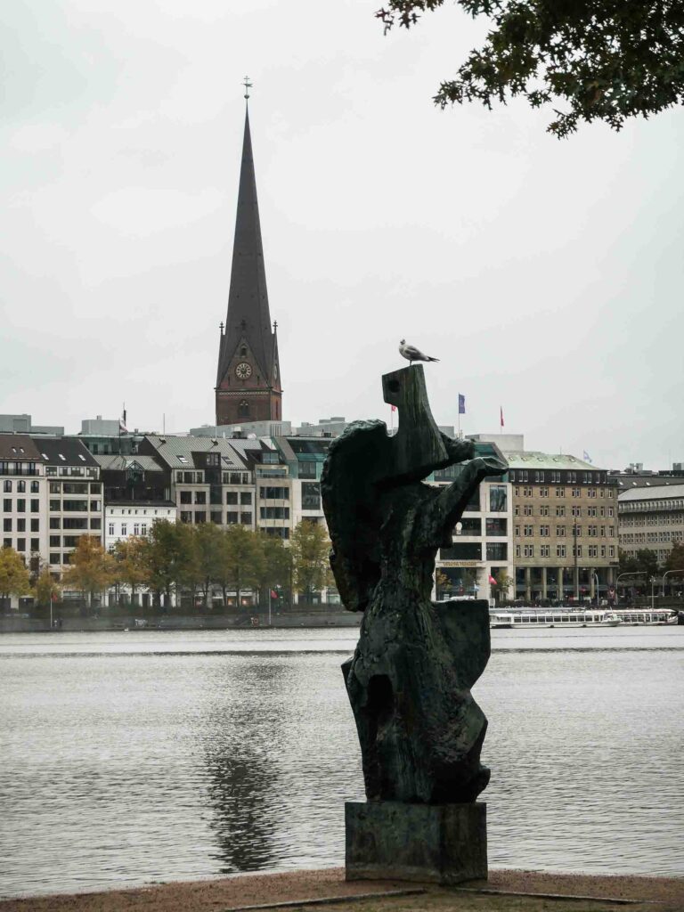 Kirche im Hintergrund, Wasserfläche und Skulptur, auf der eine Möwe sitzt Foto: Lisa Freudlsperger