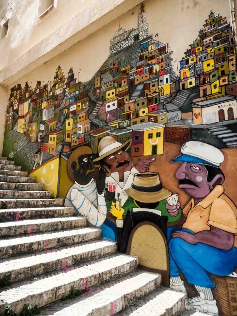 Street Art in Le Panier: Das Bild an den Stufen zeigt drei Männer, die Karten spielen und die Stadt Marseille im Hintergrund. Foto: Lisa Freudlsperger