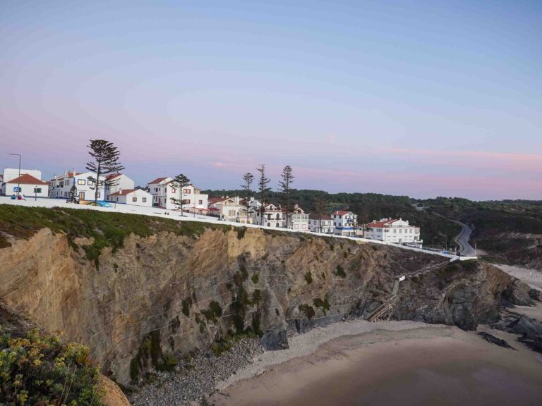 Blick auf weiße Häuser oberhalb Strand und Felsen im Sonnenuntergang Foto: Lisa Freudlsperger