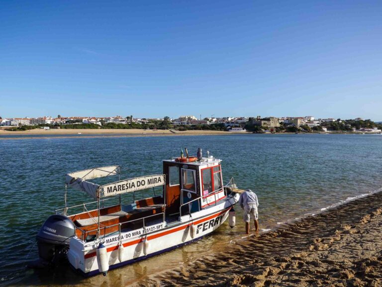 Kleines Boot auf einer Flussmündung mit Dorf im Hintergrund. Foto: Lisa Freudlsperger