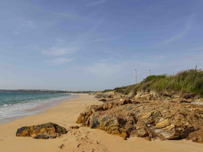 Sandstrand und Meer. In der Ferne erkennt man zwei Schornsteine. Foto: Lisa Freudlsperger